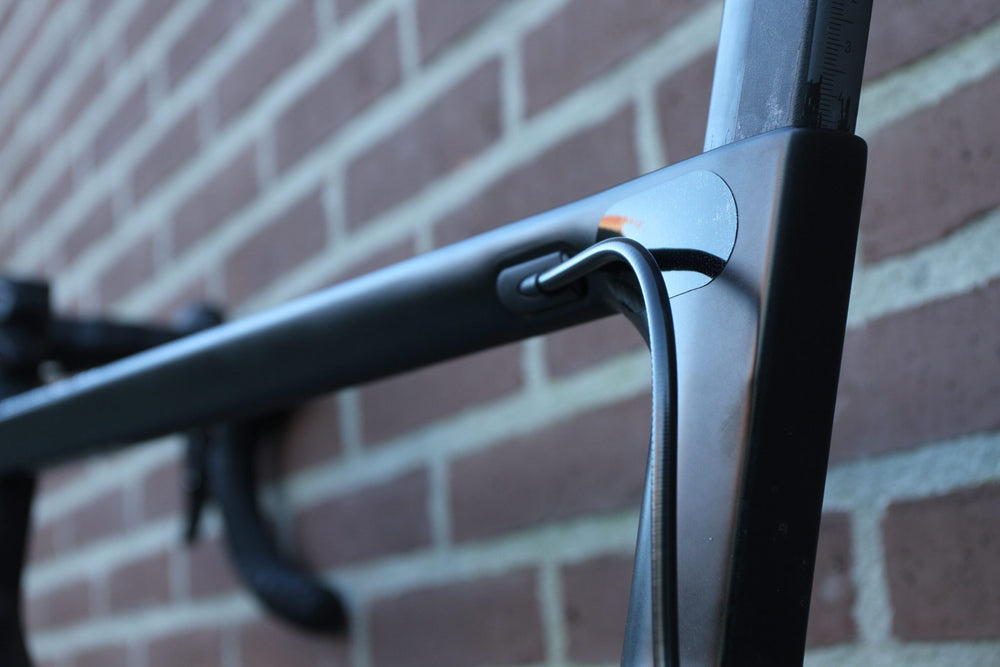 Transparante PPF-beschermfolie bij het balhoofd van een zwarte racefiets, tegen schurende kabels