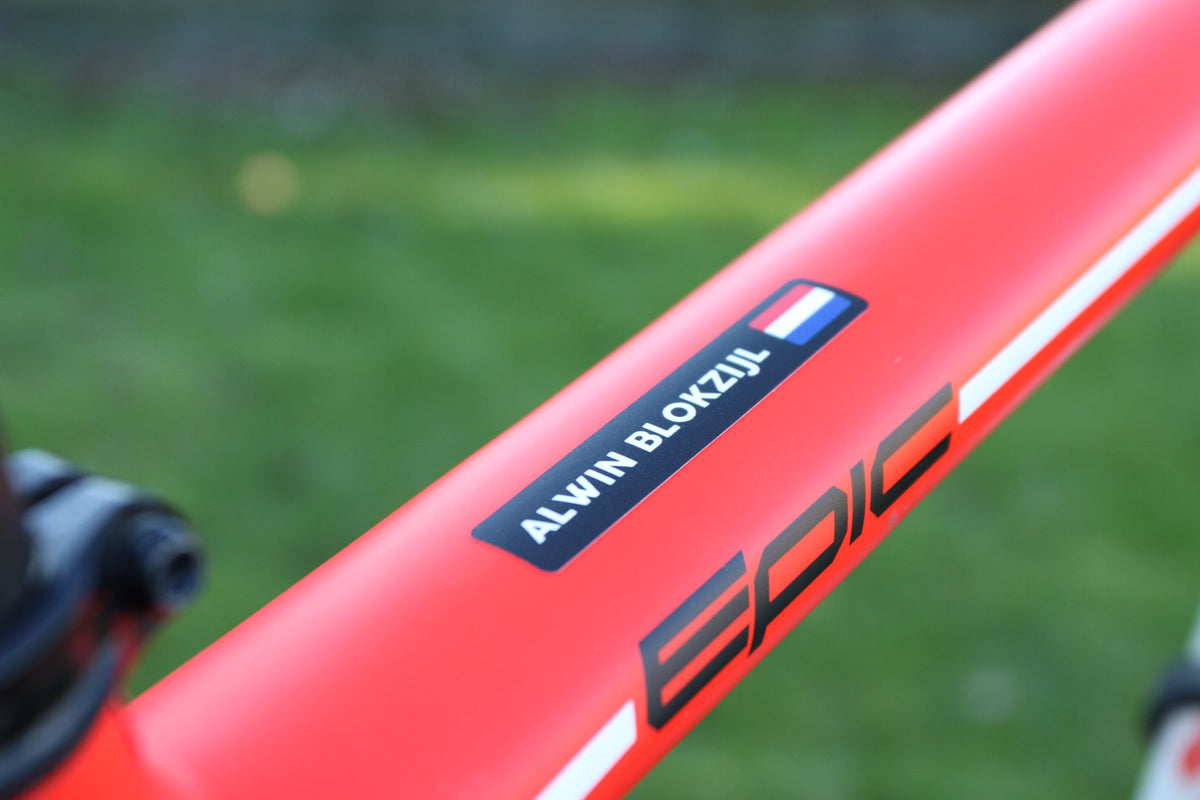 Zwarte naamsticker met Nederlandse vlag op de rode bovenbuis van een mountainbike
